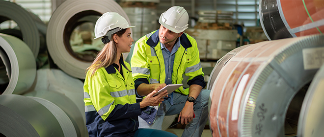 a female Ironworker journeyperson is reviewing inventory with a male apprentice at an industrial plant.