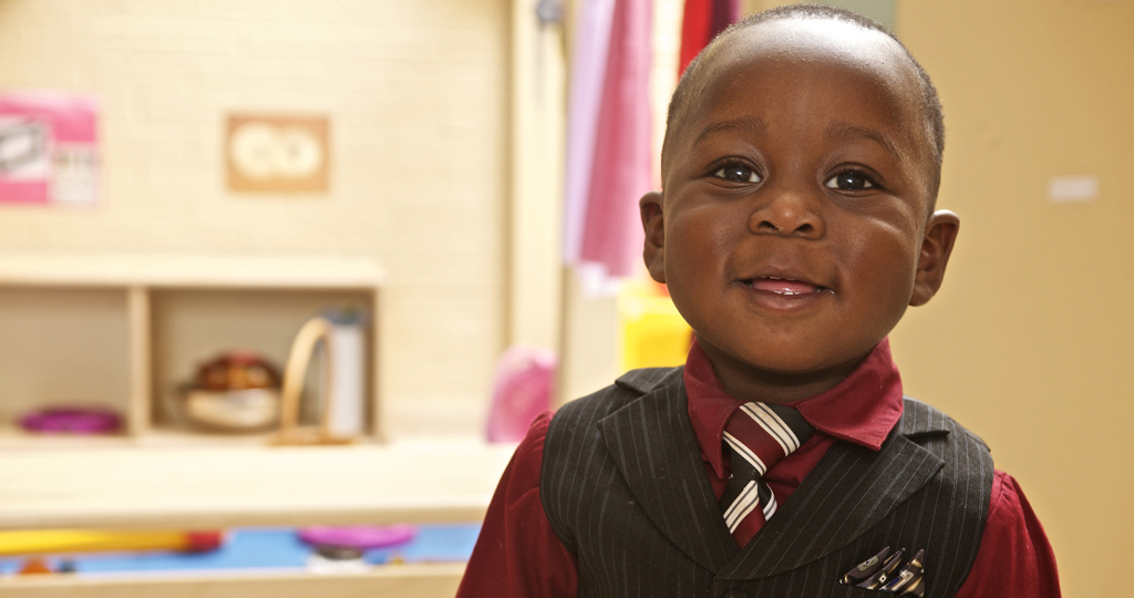 Young boy wearing a vest and tie, smiling at the camera